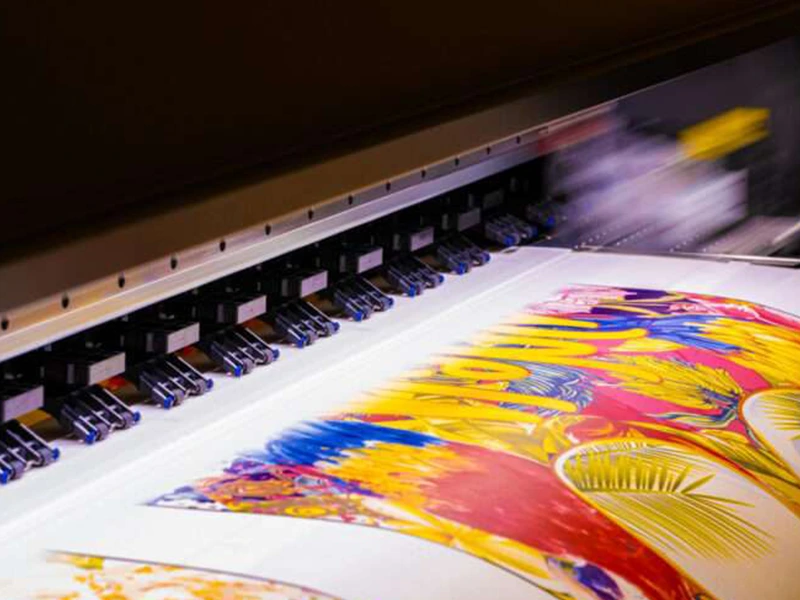 Drukarka wielkoformatowa drukująca kolorową grafikę na arkuszu materiału.