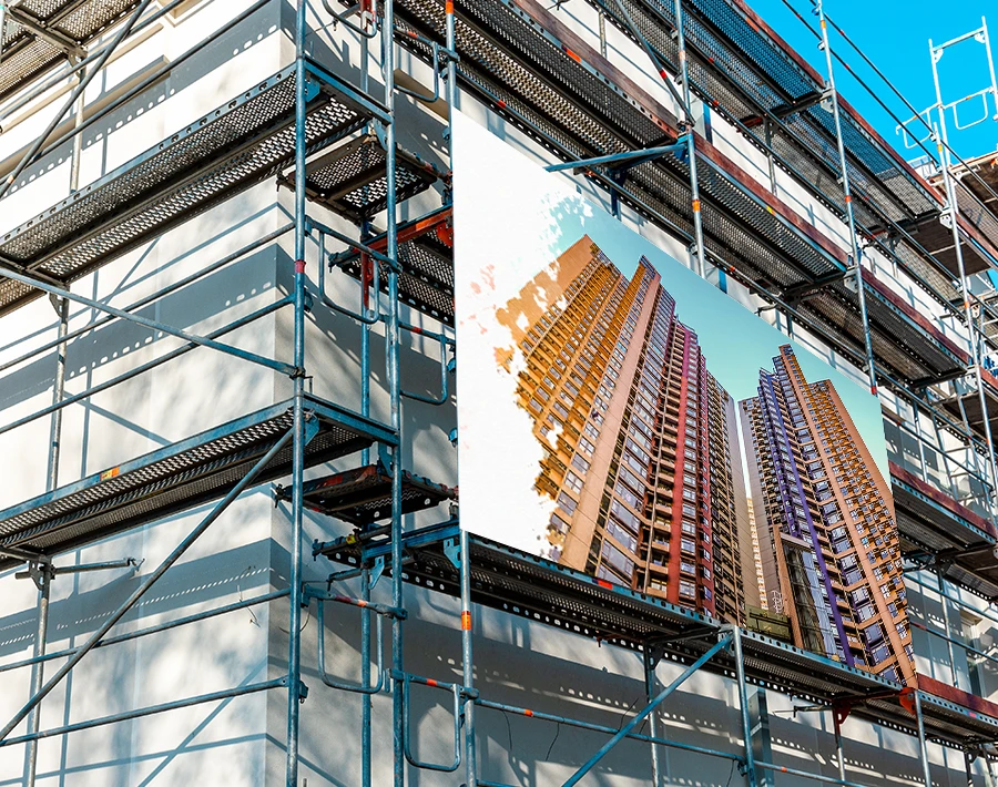 Biały baner na rusztowaniach z nadrukiem wizualizacji budynku, zamocowany na elewacji w trakcie remontu.