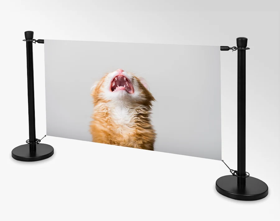 Biała barierka reklamowa z rozpiętą grafiką przedstawiającą kota między dwoma słupkami.