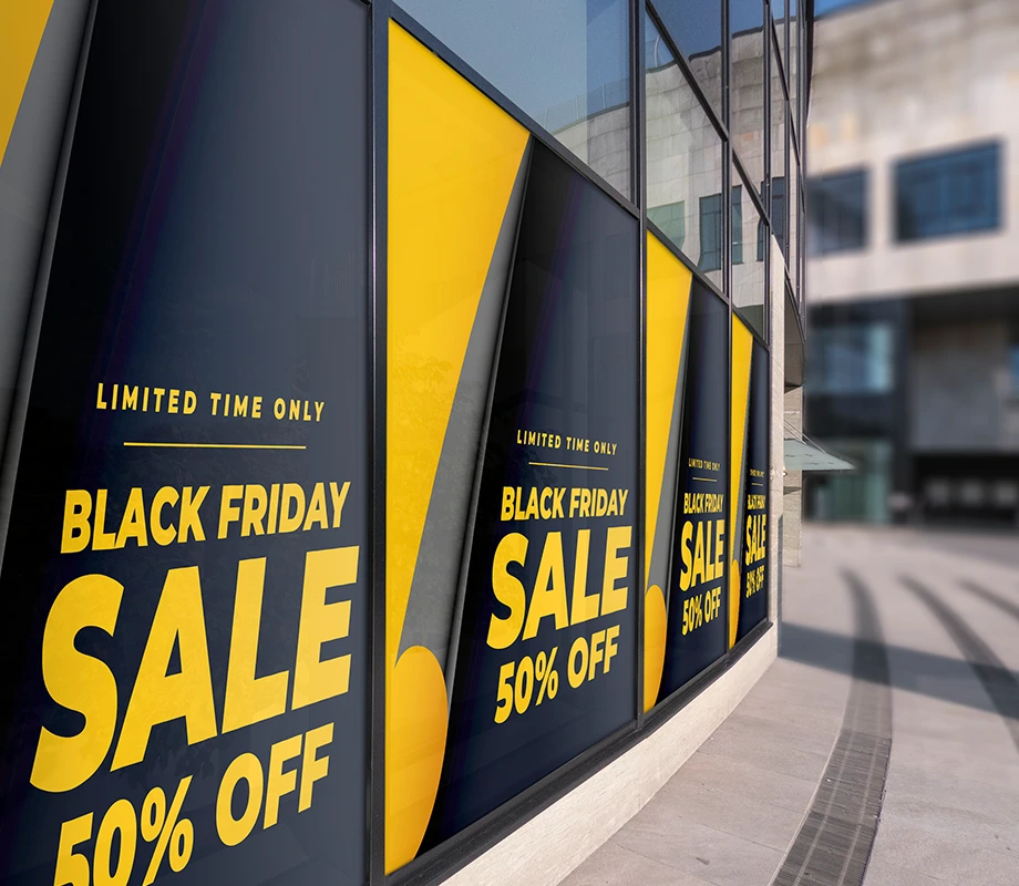 Naklejka okienna z czarno-żółtą grafiką „Black Friday Sale 50% Off” na witrynie sklepowej.