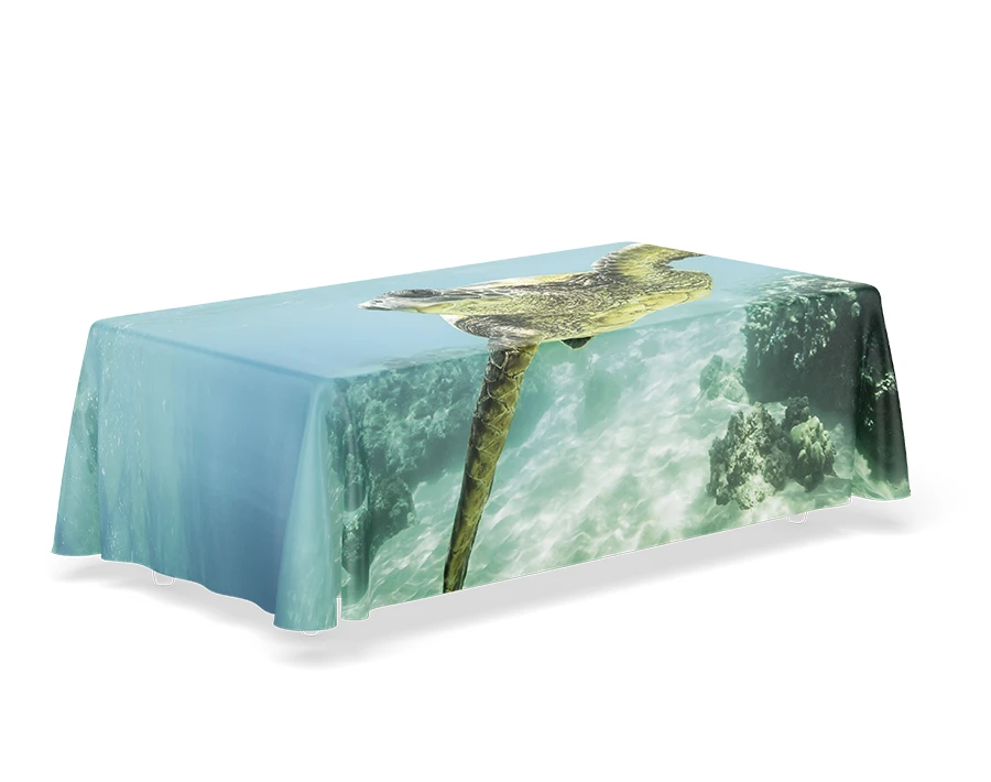 Biały stół cateringowy z obrusem z nadrukiem przedstawiającym morską falę i wybrzeże.