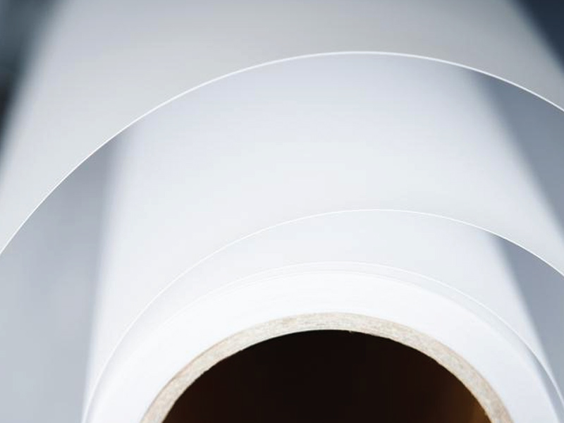 Biały papier Photo zwinięty w rolkę z widoczną gładką, matową powierzchnią.