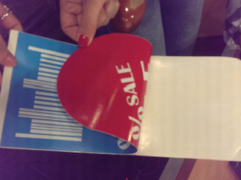 Biała naklejka dwustronna częściowo odklejana z podłoża, prezentująca warstwę klejącą.