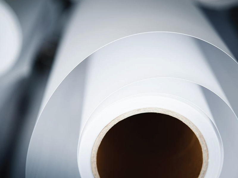 Biały materiał Keshet zwinięty w rolkę z widoczną gładką powierzchnią.