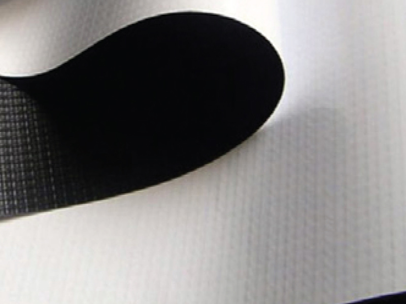 Biały materiał Frontlit Black Back z czarnym spodem, lekko podwinięty, ukazujący warstwę blokującą światło.