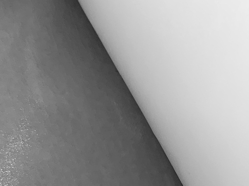 Biała folia Strong z podwiniętym rogiem, ukazująca grubszą i sztywniejszą strukturę materiału.