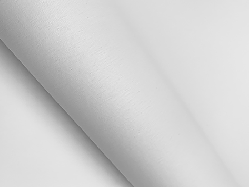 Biały materiał Airtex o gładkiej, lekko matowej powierzchni, delikatnie podwinięty.
