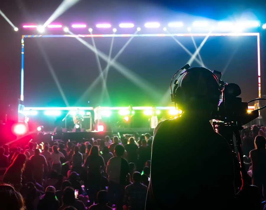 Biały baner zamocowany przy scenie koncertowej z oświetleniem i publicznością pod sceną.