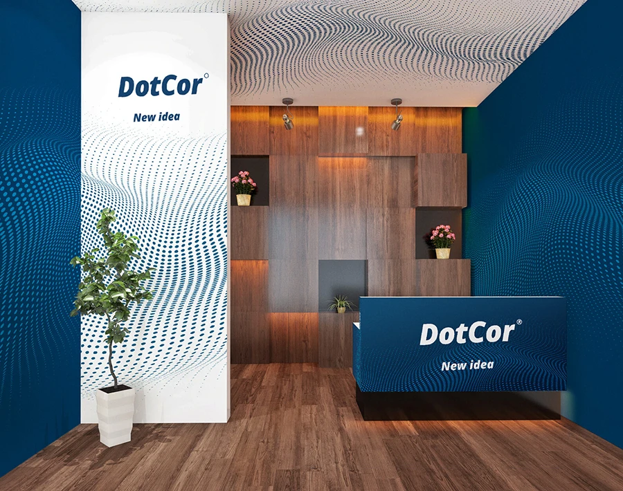 Biało-niebieskie stoisko targowe DotCor z ladą, ściankami reklamowymi i rośliną dekoracyjną.