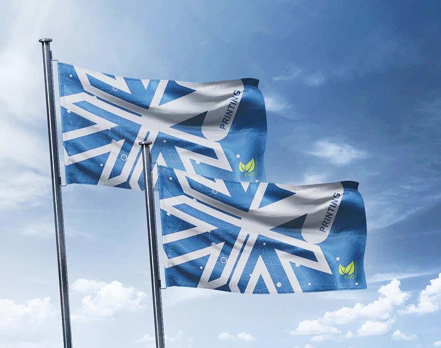 Dwie flagi z niebiesko-białą grafiką powiewają na masztach na tle pochmurnego nieba.