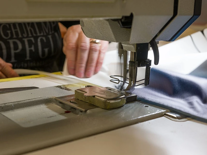 Zbliżenie na maszynę do szycia podczas zszywania materiału w procesie produkcji.