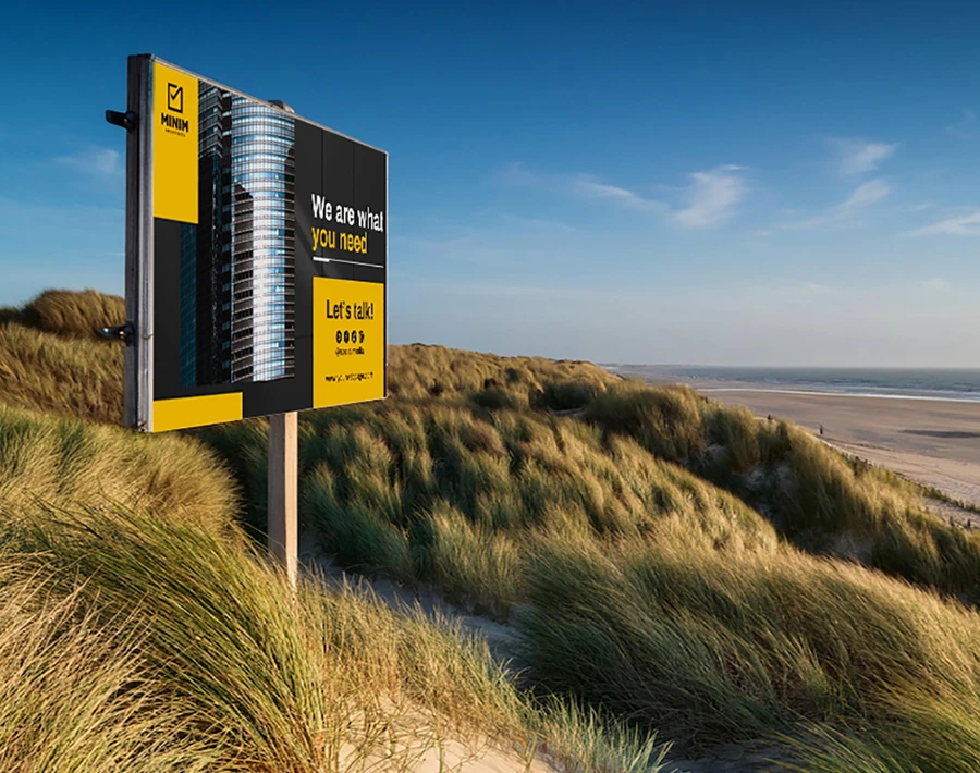 Biała tablica budowlana z nadrukiem informacyjnym ustawiona na słupach w terenie.