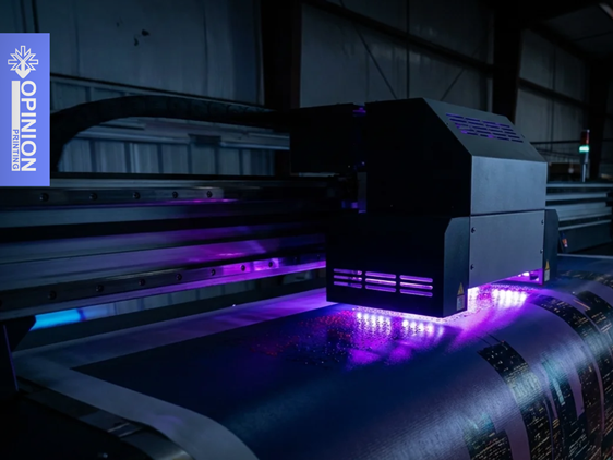 Głowica drukarki wielkoformatowej z fioletowym światłem UV drukuje grafikę na białym materiale w roli.